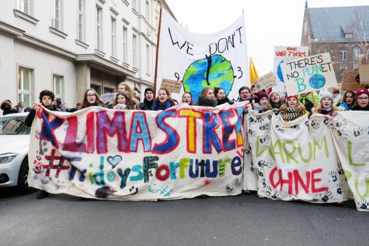 Schülerinnen gehen hinter dem Demo-Fronttransparent mit der bunt gesprayten Aufschrift: "Klimastreik – Fridays For Future".