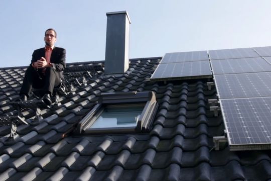 Volker Quaschning sitzt auf dem Dach und erklärt die Bürgerenergiewende.
