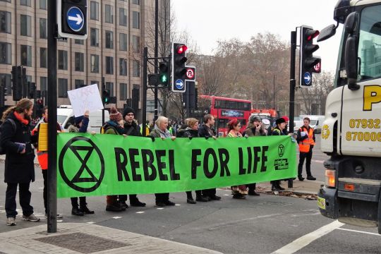 Menschen mit Transparent "Rebel for Life" stellen sich auf Kreuzung Lkw in den Weg