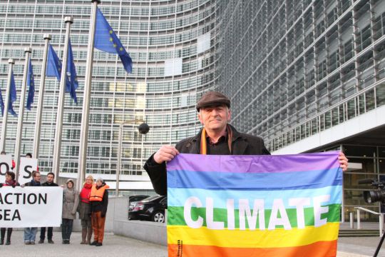 Vor dem Sitz der EU-Kommission in Brüssel hält ein Demonstrant eine Regenbogenfahne mit der Aufschrift "Klima" hoch, im Hintergrund demonstrieren weitere..