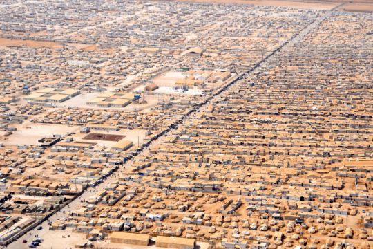 Luftbild einer quadratkilometergroßen Fläche mit Flüchtlingszelten, alles ist mit rotbraunem Staub bedeckt.