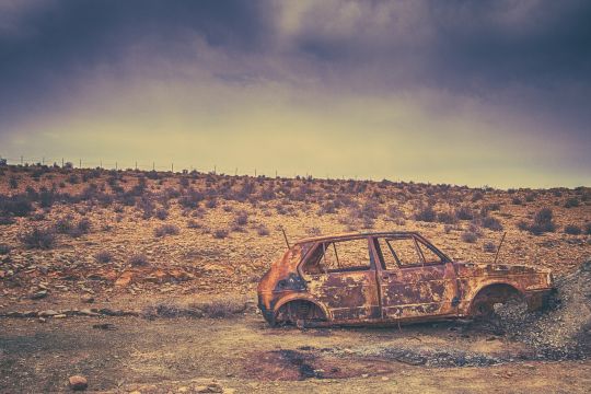 Rostiges Autowrack in der Wüste im Zwielicht.