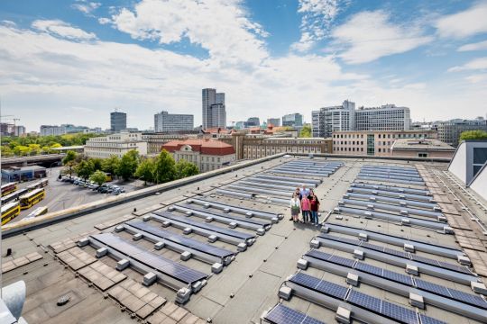 Einige aus dem Verein Solar Powers stehen auf dem Dach, sind kaum zu sehen zwischen ausgedehnten Photovoltaik-Flächen.