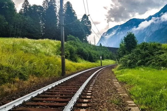 Gleis mit weißen Schienen führt durch Berglandschaft.