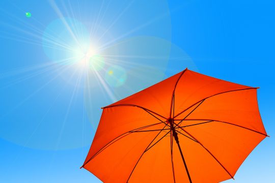 Roter Sonnenschirm vor strahlend blauem Himmel