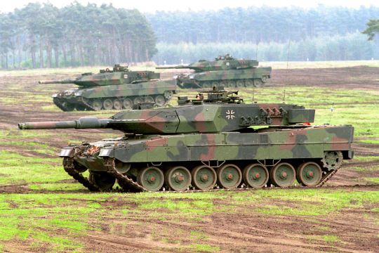 Mehrere Bundeswehr-Kampfpanzer vom Typ Leopard 2A5 fahren über ein Feld.
