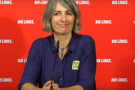 Cléo Mieulet vor einer roten Wand mit Aufschrift "Die Linke"