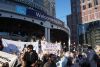 Protesierende sitzen vor einem Messegebäude, im Hintergrund ein Schild "Welcome to IAA".