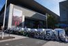 Protesierende sitzen vor einem Messegebäude mit Ballons mit der Aufschrift "autofrei".