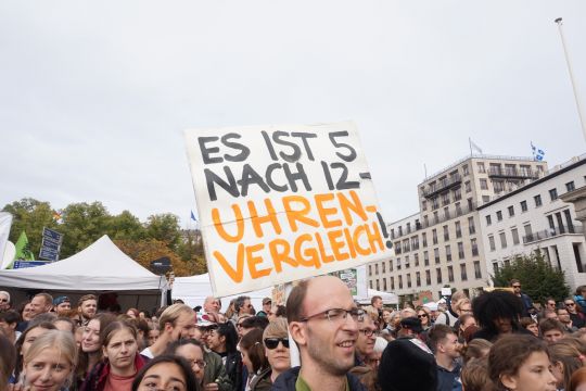 Auf einer Fridays-for-Future-Demonstration hält einer ein Schild hoch: "Es ist fünf nach zwölf – Uhrenvergleich".