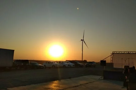Ein Windrad am Horizont vor der untergehenden Sonne.