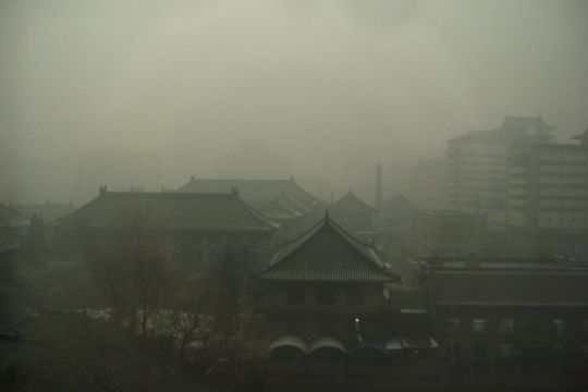 Gebäude mit geschwungenen Dächern in einem grauen Nebel, der von Verschmutzung herrührt