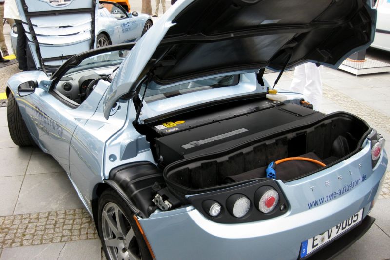 Ein Elektro-Sportwagen von hinten mit einer sehr großen Batterie im geöffnetem Kofferraum.