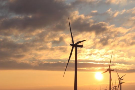 Blick auf Windkraftanlage im Meer bei untergehende Sonne