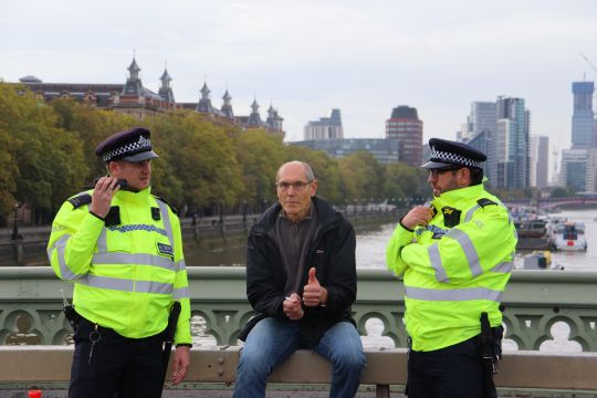 Ein Mann zwischen zwei Polizisten auf einer Londoner Brücke