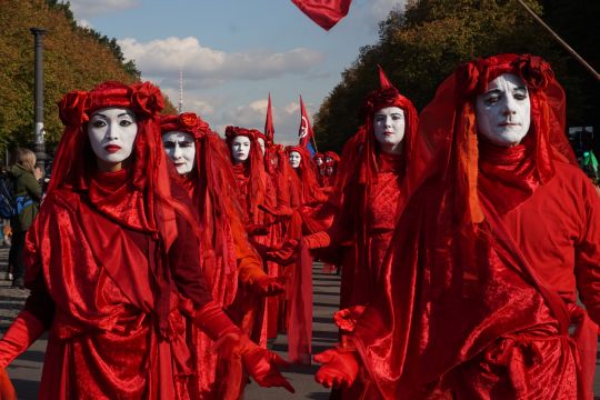 Ein Umzug von rot angezogenen Menschen mit weiß geschminkten Gesichtern