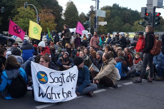 Menschen mit Banner "Sagt die Wahrheit"sitzen auf einer Straße. 