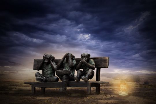 Die bekannten drei Affen sitzen wie Menschen gekleidet auf einer Bank, hinter ihnen zieht ein Unwetter herauf.