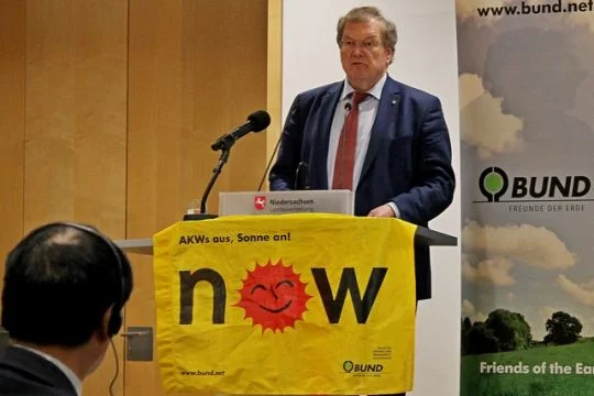 Hubert Weiger spricht an einem Poult, das mit einem Anti-Atom-Transparent behängt ist.