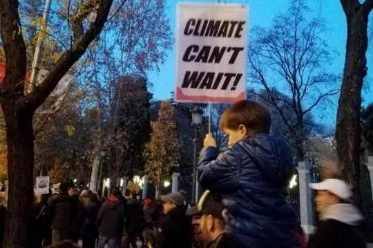 Kind mit Schild "Climate can't wait".