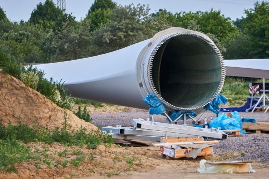 Liegendes Rotorblatt auf einer Windrad-Baustelle, das dicke Ende offen wie eine Röhre.