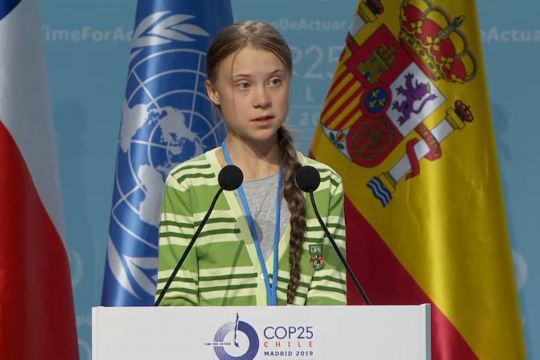 Greta Thunberg hinter Rednerpult vor drei Flaggen: Chile (Verhandlungsführung), Spanien (Gipfelaustragung) und UN