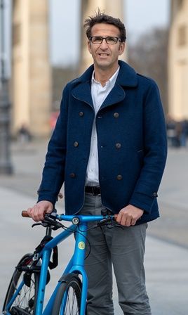 Heinrich Strößenreuther mit seinem blauen Fahrrad vor dem Brandenburger Tor.