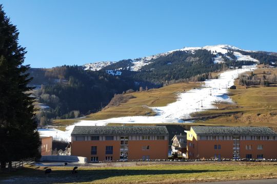 Ein Streifen Kunstschnee zieht sich über den ansonsten schneefreien Hang in Savognin im schweizerischen Kanton Graubünden.