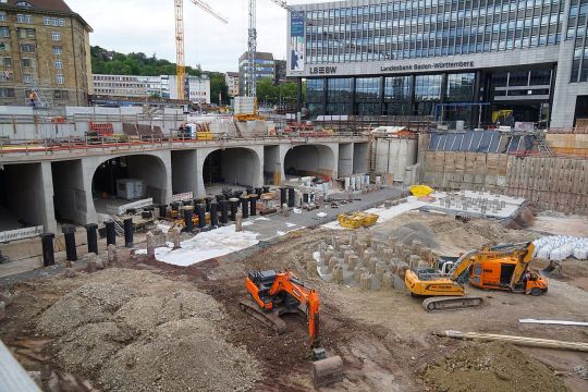 Die Baugrube für Stuttgart 21 mit einigen Gleistunneln, zwei Bagger bewegen Erdreich.