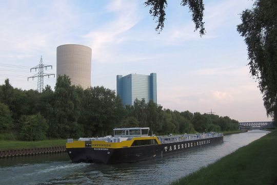 Kühlturm und Kraftwerk Datteln 4 und ein Binnenschiff auf dem Dortmund-Ems-Kanal, links die Bahnstromleitung.