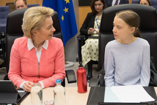 Ursula von der Leyen und Greta Thunberg sitzen nebeneinander und schauen einander an, beide mit dem jeweils typischen Gesichtsausdruck.