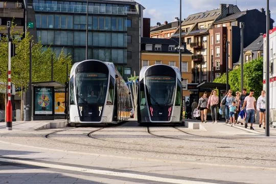 Zwei sehr moderne Straßenbahnen stehen nebeneinander an einer Haltestelle am Großen Theater in Luxemburg.