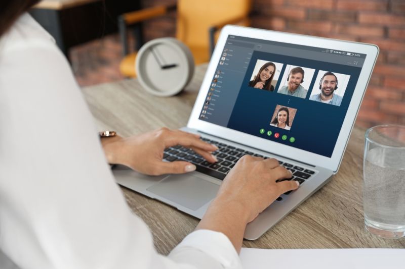 Frau verfolgt Videokonferenz mit Kolleginnen und Kollegen am Laptop.