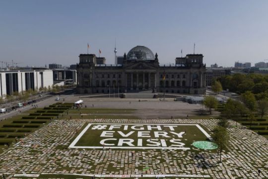 Vor dem Reichstagsgebäude in Berlin liegen Tausende Plakate, darin groß der Schriftzug "Fight every crisis", der auf die Coronakrise und die Klimakrise anspielt. 