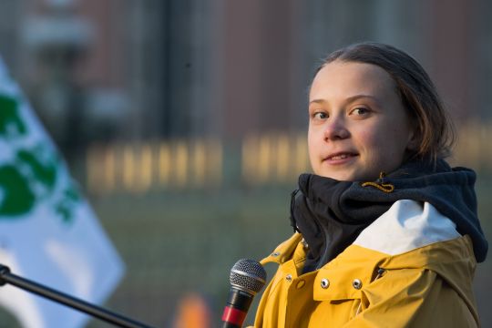 Greta Thunberg vor dem Mikrofon schaut und lächelt etwas.