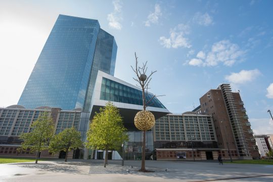 Drei kleine Bäume und eine etwas skurrile Baumskulptur vor dem Gebäude der Europäischen Zentralbank in Frankfurt am Main. 