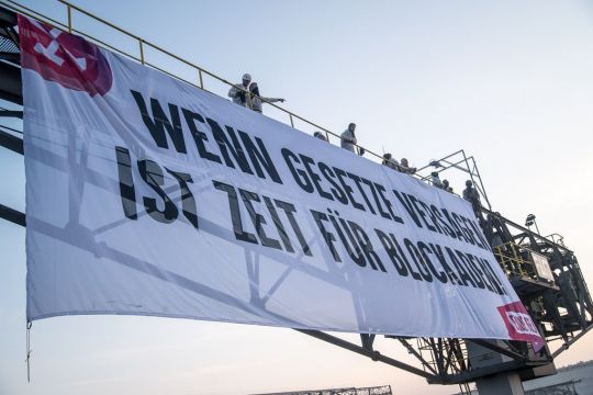 Aktivist:innen haben ein Banner an einem Bagger im Tagebau Jänschwalde befestigt: "Wenn Gesetze versagen, ist Zeit für Blockaden".