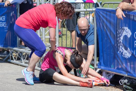 Bei einem Benefiz-Lauf während einer Hitzewelle im Sommer 2017 im englischen Southampton ist eine Läuferin zusammengebrochen und sitzt am Boden.