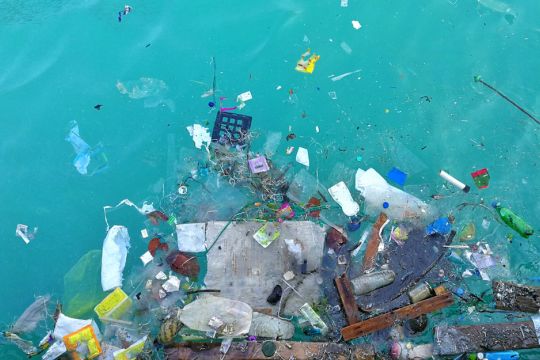 Kunststoffmüll schwimmt in türkisblauem Meerwasser, von oben aufgenommen.