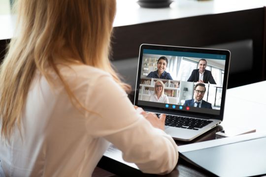 Bürochefin spricht mit Mitarbeiterinnen und Mitarbeitern, die im Homeoffice sind.