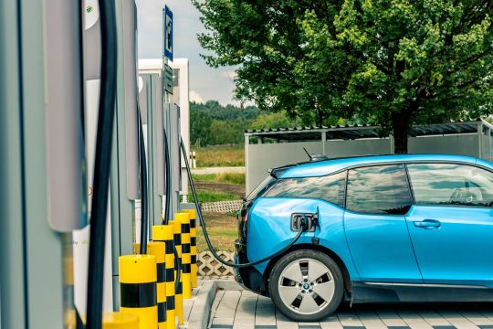 Ein blaues Elektroauto der Marke BMW i3 steht an einer von mehreren Ladesäulen auf einem Parkplatz in Bernau am Chiemsee.