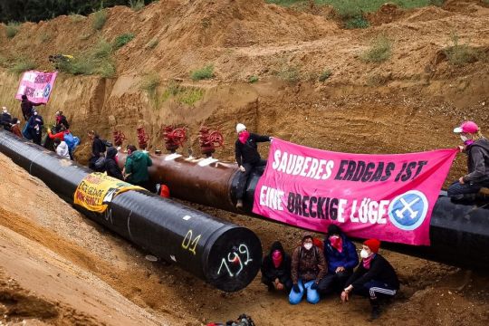 Eine Gruppe Menschen hat eine im Bau befindliche Erdgaspipeline symbolisch besetzt und hält ein Transparent hoch: "Sauberes Erdgas ist eine dreckige Lüge".