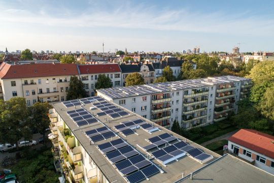 Mehrstöckige Neubaublöcke mit Flachdach, darauf Solarmodule.