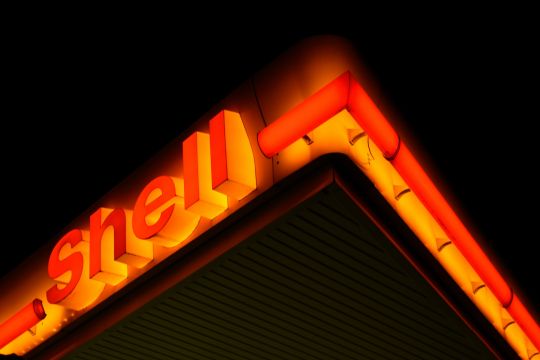 Rot-gelb leuchtende Dachumrandung einer Shell-Tankstelle in Waiblingen, schräg von unten gegen den schwarzen Nachthimmel aufgenommen.