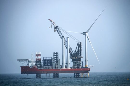 Von einer Plattform aus wird ein Offshore-Windrad errichtet.