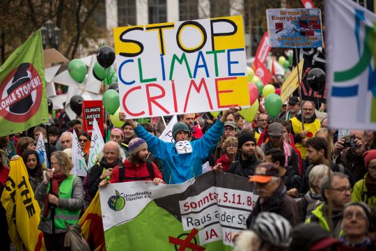 Klimademonstration in Bonn im November 2017, einer hält ein selbstgemaltes großes buntes Plakat hoch: Stop Climate Crime.