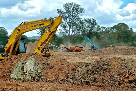 Bagger planieren ein Gelände, offenbar soll dort was gebaut werden. Im Hintergrund ein paar Bäume.