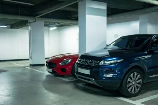 Ein großer blauer SUV und ein roter Mercedes-Sportwagen in der Tiefgarage.