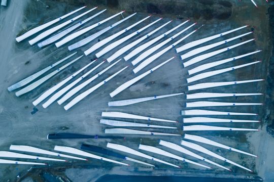 Rotorblätter für Windräder warten auf einer Lagerfläche außerhalb des Werkes auf den Versand.