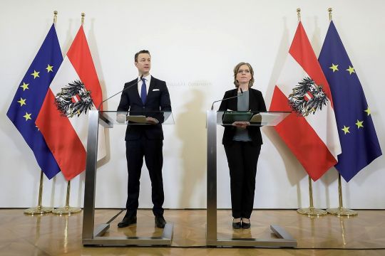 Finanzminister Gernot Blümel und Umweltministerin Leonore Gewessler stehen an Pulten, umrahmt von Flaggen Österreichs und der EU.